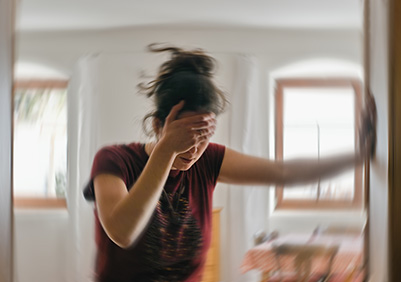 Woman holding the wall and her head while suffering from vertigo